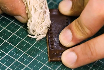 Manual edge burnishing on vegetable-tanned leather, illustrating the fiber compaction process that creates a smooth, paint-free finish with zero peeling risk.