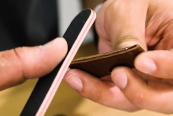Structural folded edge (rembordé) technique on premium leather, illustrating how wrapping raw edges prevents fiber fraying and enhances long-term durability.